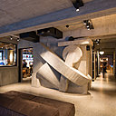 Dans le hall, béton massif ou factice et sculpture assemblée d’éléments de plafond de Jules Wabbes et Christophe Gevers avec pièces en marbre. « Le reste des murs (du lobby) est traité comme une grande sculpture constructiviste. » Lionel Jadot.