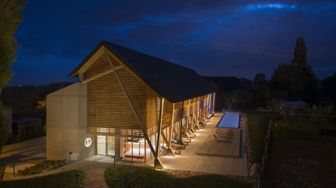 L’architecture du lieu reflète les idées directrices. Les matériaux sont nobles et bruts, la palette est très réduite : une ossature en chêne vient s’appuyer contre un volume en béton. Le tout est posé sur une pierre grise et lisse.