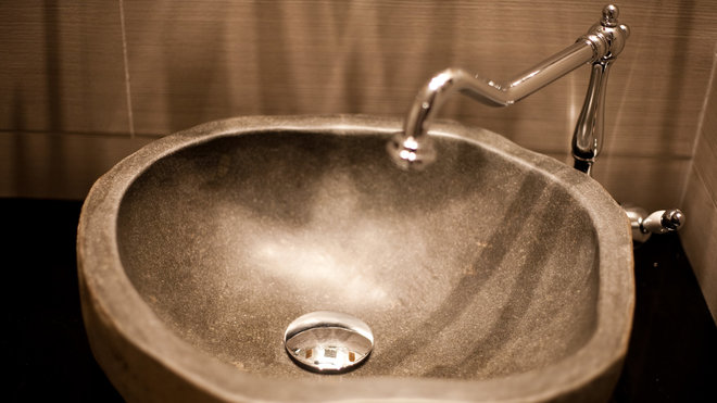 Dans une salle de bains, une vasque en céramique aux contours irréguliers qui évoquent le geste artisanal. Dans une salle de bains, une vasque en céramique aux contours irréguliers qui évoquent le geste artisanal.