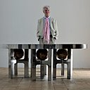 Ado Chale derrière la table monolithique Galaxy en aluminium moulé avec piètement intégrant des boules recouvertes de mosaïque.