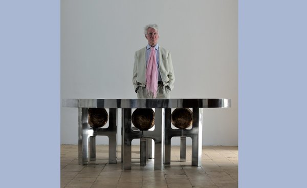 Ado Chale derrière la table monolithique Galaxy en aluminium moulé avec piètement intégrant des boules recouvertes de mosaïque.