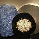 Lors de l’exposition bruxelloise à Bozar, organisée du 18 août au 24 septembre 2017, trois plateaux de table : devant, table « Cible » avec décor central en os créée, en 2011, à gauche, table « Mosaïque » en lapis lazuli, créée en 2008, et à droite, table « Lunaire » en aluminium moulé, création Chale Collection en 2008.