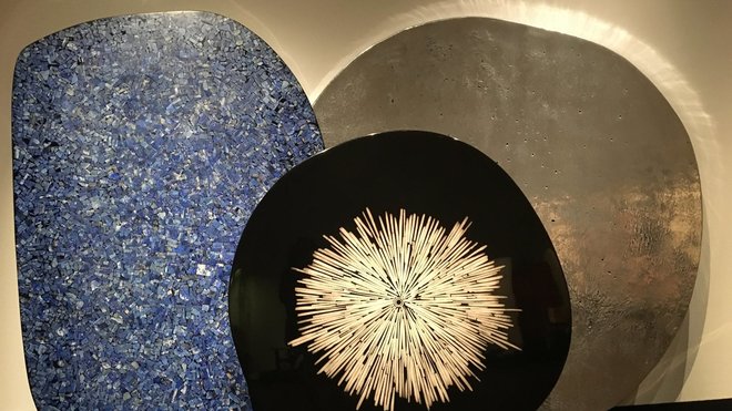 Lors de l’exposition bruxelloise à Bozar, organisée du 18 août au 24 septembre 2017, trois plateaux de table : devant, table « Cible » avec décor central en os créée, en 2011, à gauche, table « Mosaïque » en lapis lazuli, créée en 2008, et à droite, table « Lunaire » en aluminium moulé, création Chale Collection en 2008.