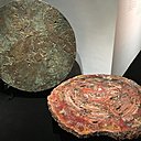 Présentées lors de l’exposition bruxelloise à Bozar, organisée du 18 août au 24 septembre 2017, table avec plateau en bois pétrifié d’Arizona, âgés de 225 ans, création en 1975. A la verticale, table « A ciel ouvert » avec plateau en fonte de bronze, création Chale Collection en 1972.