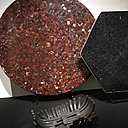Présentées lors de l’exposition bruxelloise à Bozar, organisée du 18 août au 24 septembre 2017, table en agate cornaline rouge orangé, création Chale Collection en 1990 et modèle serti d’aluminium avec mosaïque en onyx noir, création Chale Collection en 1971. Au sol, coupe « Brasero » en fer forgé, création Chale collection en 1970.