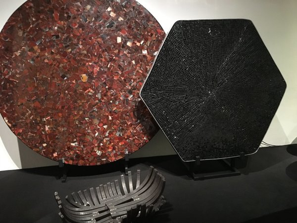 Présentées lors de l’exposition bruxelloise à Bozar, organisée du 18 août au 24 septembre 2017, table en agate cornaline rouge orangé, création Chale Collection en 1990 et modèle serti d’aluminium avec mosaïque en onyx noir, création Chale Collection en 1971. Au sol, coupe « Brasero » en fer forgé, création Chale collection en 1970.