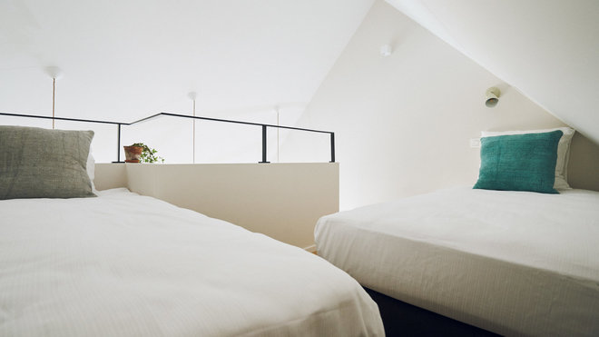 Sur la mezzanine, deux lits immaculés de couleur blanche pour accentuer l’effet de lumière naturelle et agrandir l’espace.