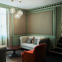 Un petit salon permet de se détendre dans l’intimité ; le vert doux, comme fil conducteur, les assises confortables, les panneaux façon tapissier, contribuent à rendre la pièce chaleureuse.