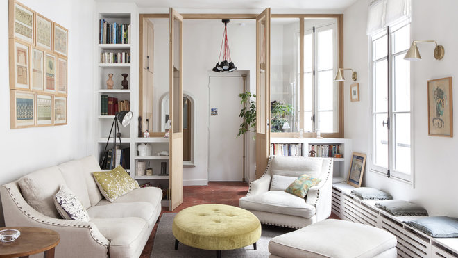 Le salon est séparé de l’entrée par une porte vitrée encadrée de rangements qui n’encombrent pas l’espace au sol.