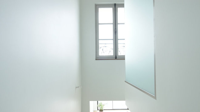 Dans la trémie de l’escalier, la boîte en verre sablé en porte-à-faux renferme la douche de la salle de bains de la suite parentale.