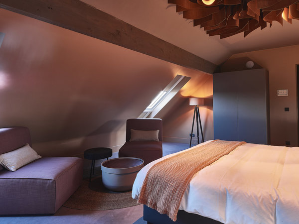 En ciel de lit, des lamelles de bois qui serpentent et rayonnent tout en diffusant la lumière douce de rampes habilement dissimulées.