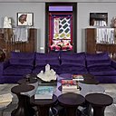 Table de salon en chêne massif teinté noir et recouverte de feuille d’argent hommage au tabouret iconique Tam Tam en forme en diabolo, créé en 1968 par le designer français Henry Massonnet. Derrière le canapé recouvert d’une housse en textile violet pour le protéger des griffes du chat, et de part et d’autre de la porte de la chambre d’amis, meubles symétriques en chêne vernis inspirés par le style des années 1940.