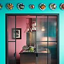 Au-dessus de la porte en verre armé qui sépare la salle à manger de la cuisine une collection d’assiettes en porcelaine avec trompe l’œil de fruits en relief réalisés par l’artiste Christine Viennet.