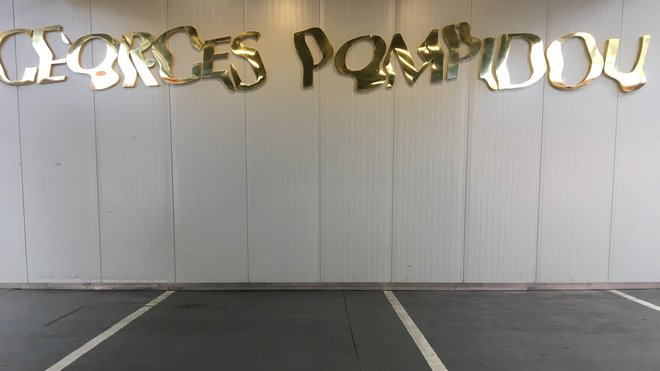 Georges Pompidou, œuvre de Raymond Hains, 1990. Caractères typographiques en laiton doré qui rendent hommage au président de la République Française qui a beaucoup travaillé pour la reconnaissance de l’art contemporain et du design ! Les lettres qui composent cette œuvre semblent issues de la vision d’un baigneur resté sous l’eau qui regarderait l’inscription se former à la surface. Kanal/Centre Georges Pompidou.