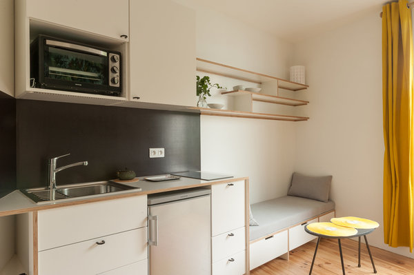 La cuisine aménagée avec des éléments Ikea est encadrée de panneaux en contreplaqué de bois filmé stratifié. Ses placards s’intègrent dans la continuité du coin salon comme si tout avait été réalisé sur mesure.