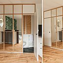 Le coin toilette avec lavabo, comme la douche, est caché derrière une porte de placard. En partie haute, des cadres en bois brisent la trop importante verticalité des miroirs.