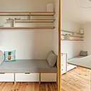 Le coin salon est composé d’une banquette qui offre un couchage d’appoint pour une personne. Sous le divan, des rangements fermés et en hauteur des étagères décoratives.