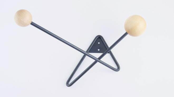 Composé d’un seul fil d’acier plié qui évite une soudure supplémentaire et renforce la solidité de la matière, patère double Atome avec boules en bois de hêtre de diamètres différents.