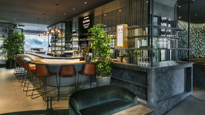 Au bar du restaurant, bois brûlé pour le comp­toir du bar et cuir pour les hauts tabourets.