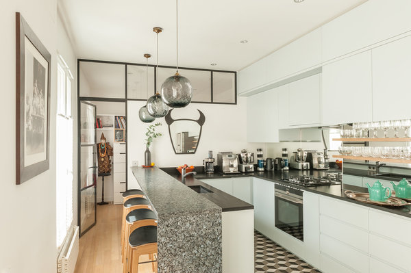 La cuisine n’a pas changé de place, mais s’est agrandie et ouverte sur l’espace de vie commun. Au fond, l’atelier de la propriétaire, créatrice de bijoux, éclairé par une verrière en partie haute.