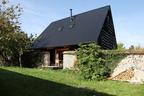 Entre l’ancien et le neuf, la frontière n’est pas visible. Les architectes de l’agence Arba n’ont pas choisi de démolir le mur pour réutiliser éventuellement ses éléments dans la nouvelle construction. De l’extérieur, on n’aperçoit que le toit et le cœur de la pièce centrale avec une petite terrasse débordante et perçant le mur existant.