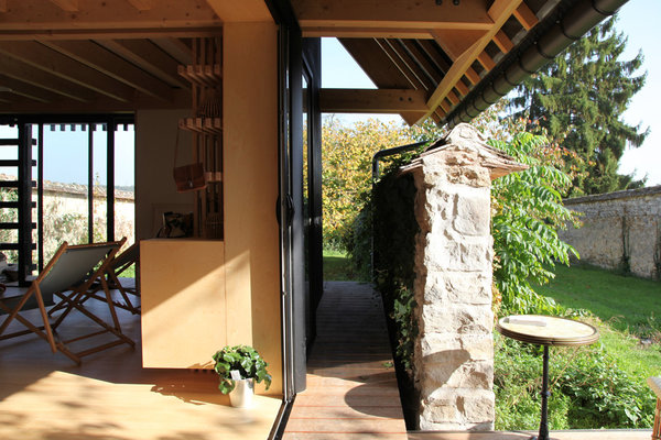 La maison est entourée d’une terrasse en bois périphérique qui permet d’accéder au jardin derrière le mur.