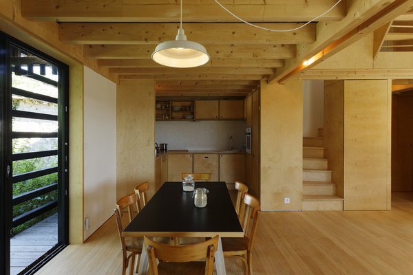 La cuisine intégrée en bois se confond avec les murs recouverts de panneaux MFP.