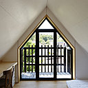 Le mur pignon de la maison est percé d’une fenêtre avec balcon qui reprend la forme du toit pentu et pointu.