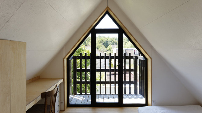Le mur pignon de la maison est percé d’une fenêtre avec balcon qui reprend la forme du toit pentu et pointu.