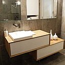 La salle de bains, nappée d’un carrelage minéral, est dotée d’un meuble dessiné par Carl Tran. Composé de deux blocs décalés, il offre une certaine légèreté visuelle qui change des modèles classiques et bénéficie d’une surface supplémentaire pour poser les affaires de toilette.