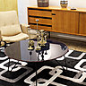 Dans la Galerie Toulousaine, table basse des années 1950 avec piètement tubulaire coudé. Enfilade de Gérard Guermonprez en chêne clair avec 2 portes coulissantes et tiroirs sur piètement en métal laqué noir, années 1950.