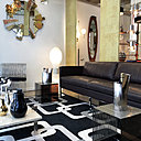 Dans la Galerie Toulousaine, ambiance année 1970 avec des bouts de canapé en plexiglas brut et tiges en métal chromé. Canapé en cuir d’origine. Miroir rond à facettes avec décor en métal rosé, doré et chromé.