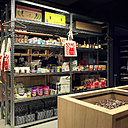 Dans l’épicerie, étagères métalliques de stockage d’esprit industriel et meubles vitrines en bois.