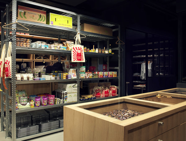 Dans l’épicerie, étagères métalliques de stockage d’esprit industriel et meubles vitrines en bois.