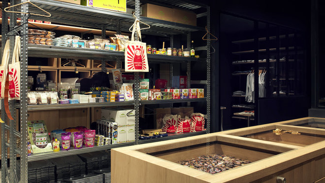 Dans l’épicerie, étagères métalliques de stockage d’esprit industriel et meubles vitrines en bois.
