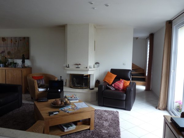 Le salon avant les travaux : un espace, maladroitement meublé et  tournant le dos à une cheminée classique. Une surface alourdie par la présence de deux fauteuils en cuir noir et rotin aux formes compactes.