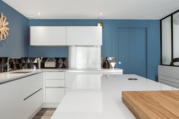 Les murs de la cuisine sont recouverts d’un bleu mat doux (La Seigneurerie). Carrelage noir mat et brillant, Diamond chez Soleras.