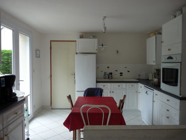 La cuisine avant : Un plan de travail réduit et une petite table rajoutée pour les repas rapides. Un muret inutile.