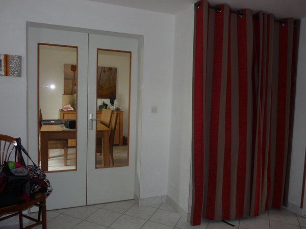 L’entrée avant les travaux de rénovation : une double porte inutile, un rangement insuffisant caché par un rideau.