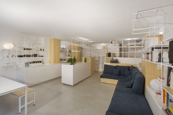 Un grand canapé d’angle est inséré dans l’architecture des rangements et épouse ses lignes.