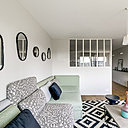 Dans la cuisine, une étagère cimaise pour mettre en valeur des cadres fait écho à celle de la salle à manger pour créer un sentiment d’unité et lier les trois espaces cuisine, salon et salle à manger. Au-dessus, appliques lumineuses en porcelaine, modèle light.005.c.w, chez Zangra.