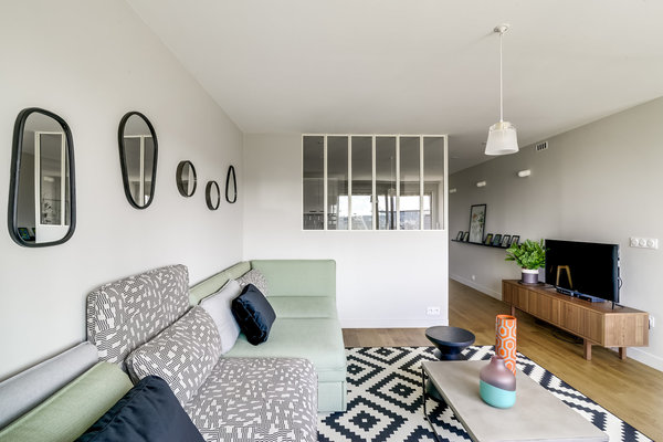 Dans la cuisine, une étagère cimaise pour mettre en valeur des cadres fait écho à celle de la salle à manger pour créer un sentiment d’unité et lier les trois espaces cuisine, salon et salle à manger. Au-dessus, appliques lumineuses en porcelaine, modèle light.005.c.w, chez Zangra.