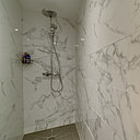 Douche à l’italienne tapissée de marbre et bac à fleur de sol en grès cérame.