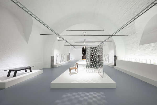 A droite de la Fade Out-chair, avec pieds en acrylique peint en dégradé qui crée un effet aérien, paravent Fragment en aluminium et cristal extra-light trempé avec décor de damiers rectangulaires et effet de miroir double face. Création Nendo éditée par Glas Italia.