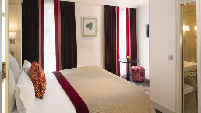 Les détails graphiques des rideaux en velours font écho aux couleurs du pouf et du dessus de lit gansé de rouge.