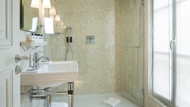 La pâte de verre nacrée éclaire la douche à l’italienne et offre son côté précieux et délicat à l’espace.