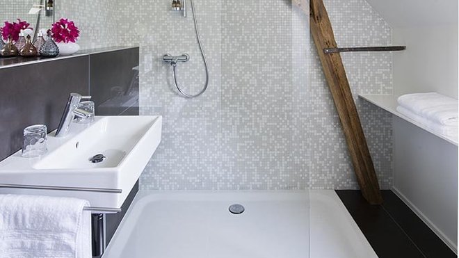 Les murs des salles de bains sont recouverts d’une mosaïque en pâte de verre et les sols de grandes dalles rectangulaires de grès cérame qui agrandissent l’espace.