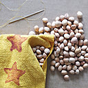 9. Une fois le coussin cousu, retournez-le sur l'endroit et remplissez-le de noyaux de cerises. refermez bien l'angle sur le gland.