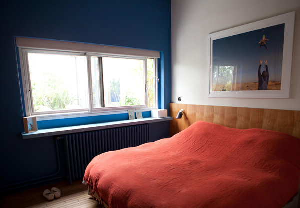 Dans la chambre, un mur peint met en valeur la fenêtre qui offre une vue cadrée sur l’extérieur.