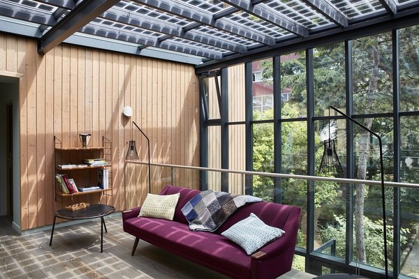 Entre ciel et terre, une grande verrière, au centre de la maison, abrite des espaces partagés pour se détendre et échanger (bibliothèque, salon...).